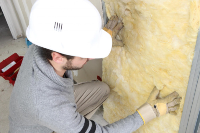 Man adding insulation to wall: Gagne Energy Savings Blog