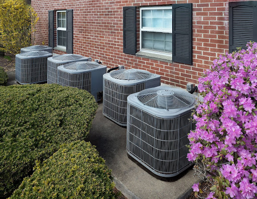 Six outdoor central air conditioning units lined up outside of a housing complex in Atlanta, GA.