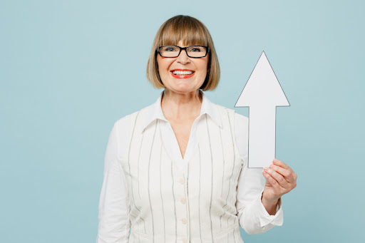 A woman holding a paper arrow that's pointed upward.