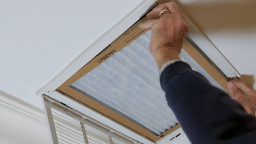 Gagne HVAC technician installing new, clean air filter in air vent.